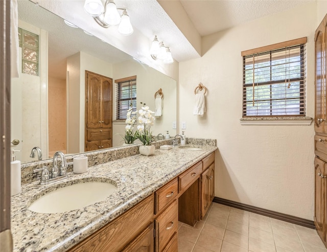 full bathroom featuring double vanity, tile patterned floors, baseboards, and a sink