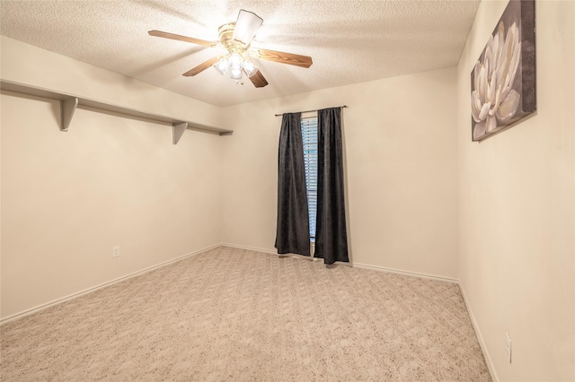 empty room with a textured ceiling, a ceiling fan, baseboards, and light carpet