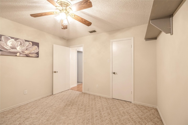 unfurnished bedroom featuring ceiling fan, carpet flooring, a textured ceiling, and visible vents