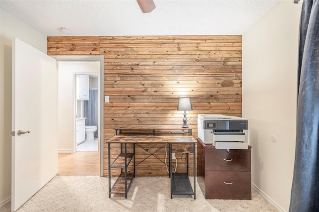unfurnished office featuring wooden walls, a textured ceiling, and baseboards
