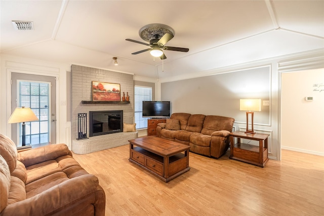 living area featuring light wood-style flooring, visible vents, lofted ceiling, a ceiling fan, and a fireplace