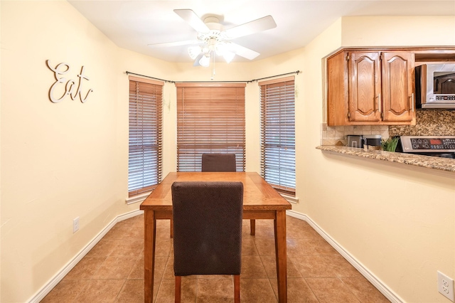 dining area with baseboards, ceiling fan, and light tile patterned flooring