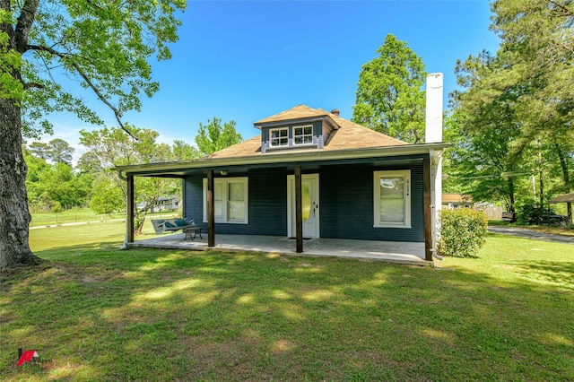 rear view of house featuring a lawn and a chimney