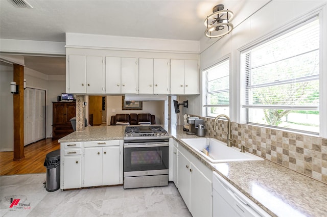 kitchen with a sink, decorative backsplash, light countertops, white cabinets, and stainless steel range with gas stovetop
