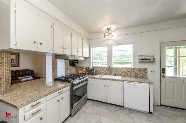 kitchen featuring white cabinets, a sink, backsplash, white dishwasher, and stainless steel gas stove