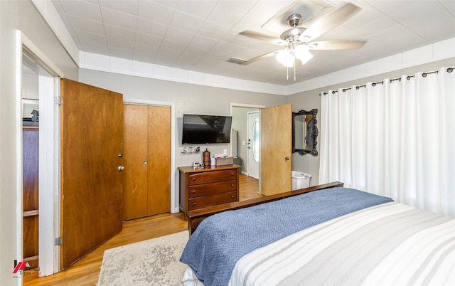 bedroom with light wood-style floors, visible vents, a closet, and ceiling fan