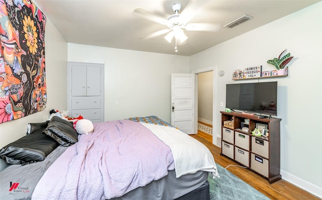 bedroom with ceiling fan, baseboards, wood finished floors, and visible vents