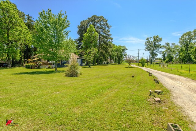 view of property's community featuring a yard and dirt driveway