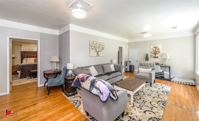 living room with visible vents, crown molding, and light wood finished floors