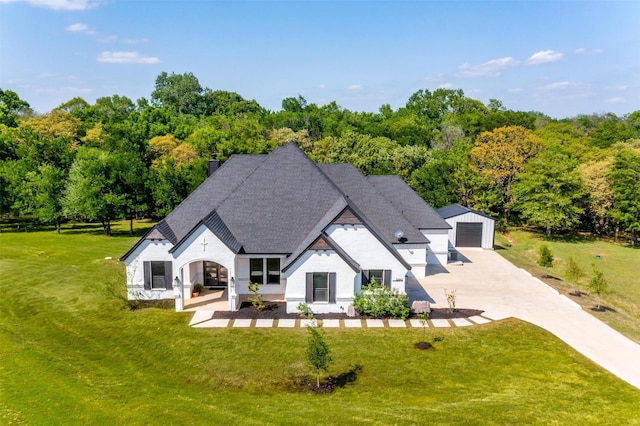 rear view of property featuring a yard, concrete driveway, an outbuilding, roof with shingles, and a garage