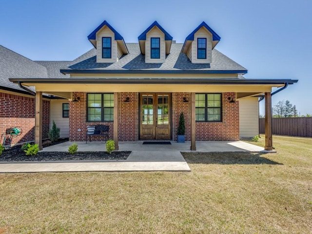 view of front of property featuring fence, french doors, a front yard, and brick siding