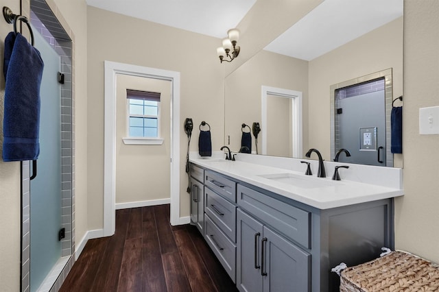 full bath featuring baseboards, wood finished floors, a sink, and double vanity