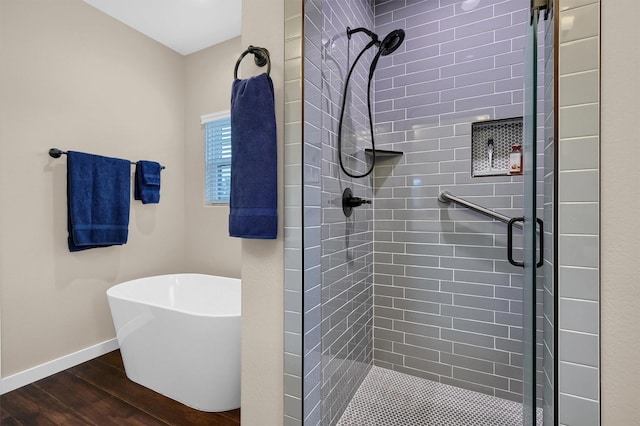 full bath with a freestanding bath, a shower stall, wood finished floors, and baseboards