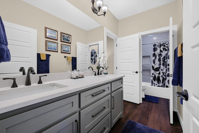 full bathroom with toilet, wood finished floors, a sink, and double vanity