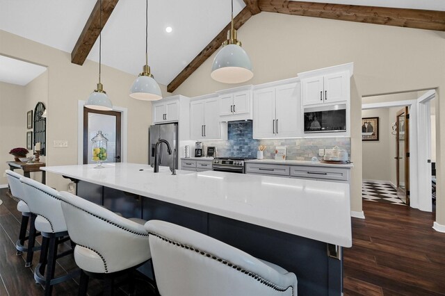 kitchen with dark wood-style floors, stainless steel appliances, backsplash, beamed ceiling, and a spacious island
