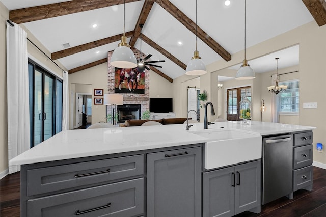 kitchen with stainless steel dishwasher, gray cabinetry, a sink, and dark wood finished floors