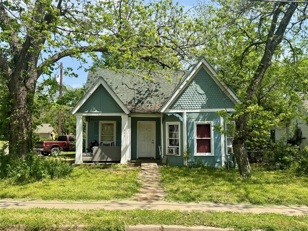 view of front of property with roof with shingles, a front lawn, and covered porch