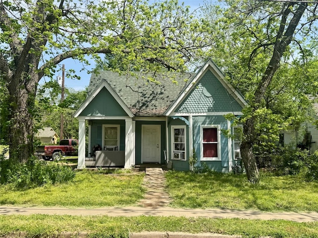 view of front of property with roof with shingles, a front lawn, and covered porch