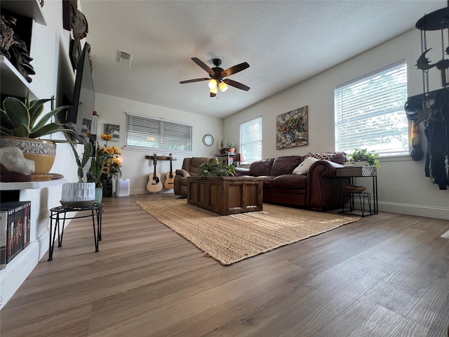 108 E Neely Ave, Comanche, TX 76442 - living area featuring a textured ceiling, baseboards, visible vents, wood finished floors, and ceiling fan