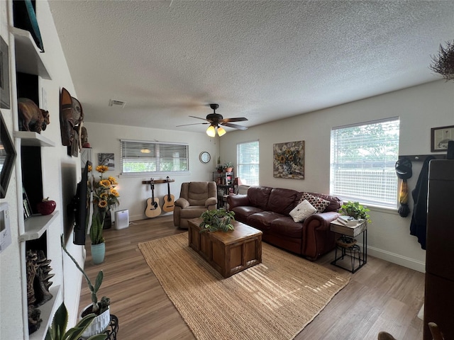 108 E Neely Ave, Comanche, TX 76442 - living area with a textured ceiling, light wood-style floors, visible vents, and a ceiling fan