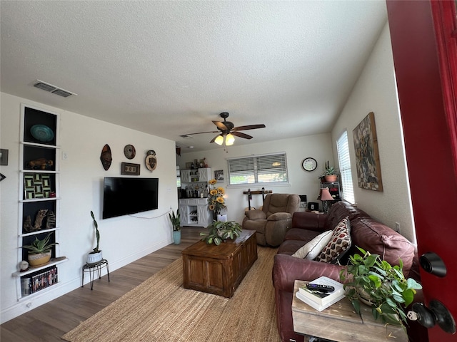 108 E Neely Ave, Comanche, TX 76442 - living room featuring ceiling fan, wood finished floors, visible vents, and a textured ceiling