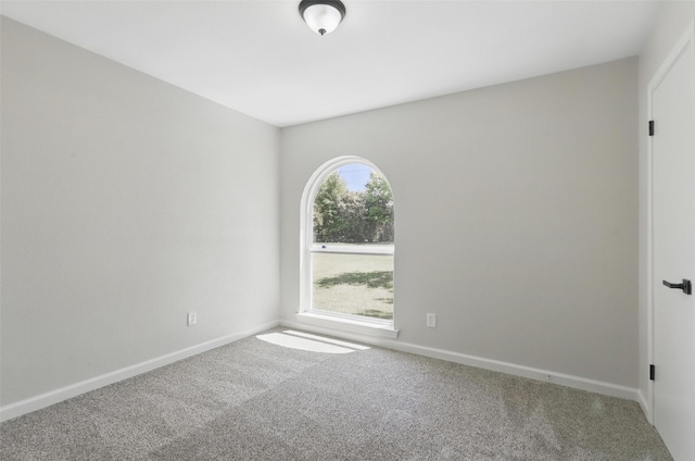 carpeted empty room featuring baseboards