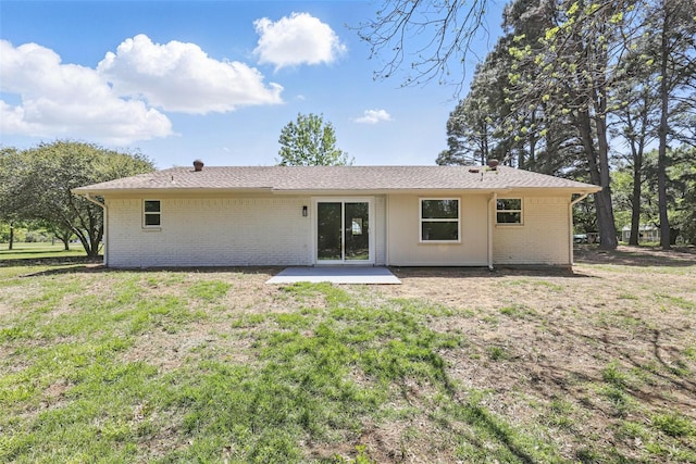 rear view of house featuring brick siding, a yard, and a patio