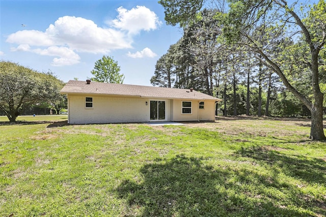 rear view of property with brick siding and a lawn