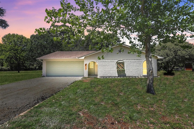 single story home with a front lawn, driveway, brick siding, and a garage