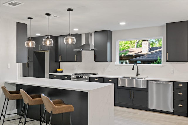 kitchen with stainless steel appliances, a sink, visible vents, wall chimney range hood, and a breakfast bar area