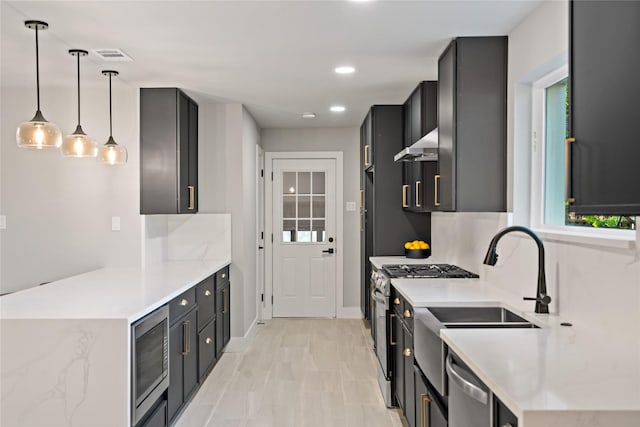 kitchen with baseboards, visible vents, exhaust hood, appliances with stainless steel finishes, and hanging light fixtures