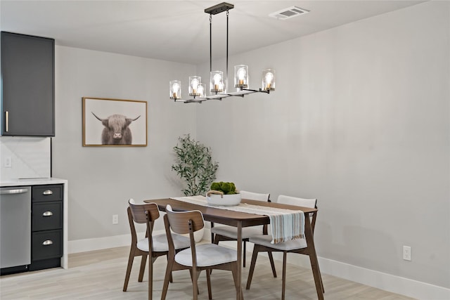 dining room featuring baseboards, a chandelier, visible vents, and light wood-style flooring