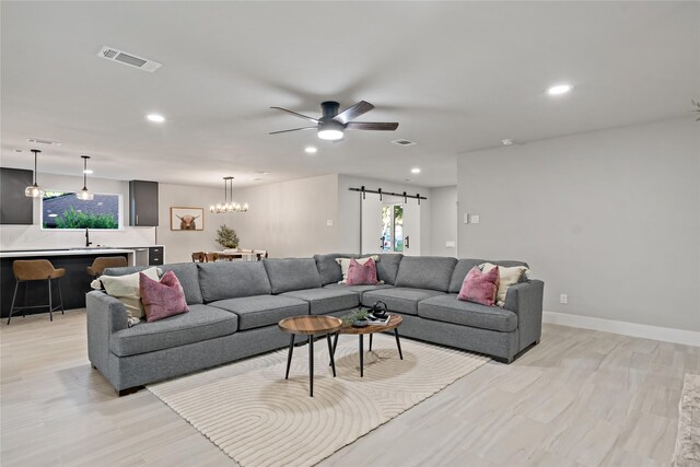 living room with a barn door, plenty of natural light, visible vents, and recessed lighting