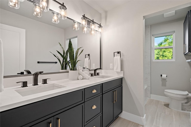 bathroom featuring double vanity, toilet, baseboards, and a sink