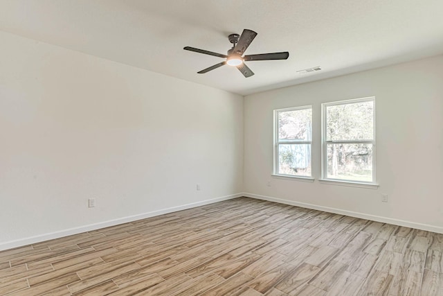 unfurnished room with baseboards, a ceiling fan, light wood-style floors, and visible vents