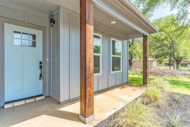 property entrance with board and batten siding and fence