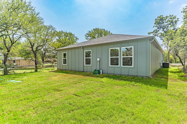 rear view of property with a lawn, cooling unit, fence, and board and batten siding