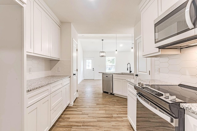 kitchen featuring backsplash, stainless steel appliances, white cabinets, and a sink