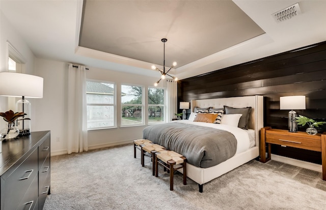 bedroom with light colored carpet, baseboards, visible vents, and a raised ceiling