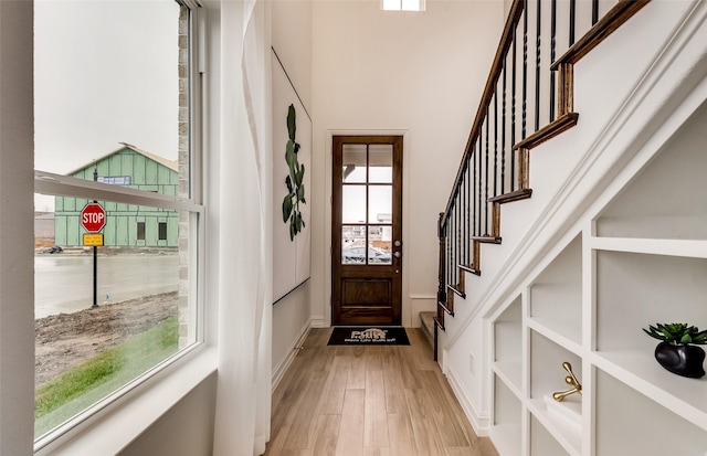 entryway with a high ceiling, stairs, and light wood finished floors