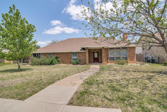 single story home featuring fence, a front yard, and brick siding