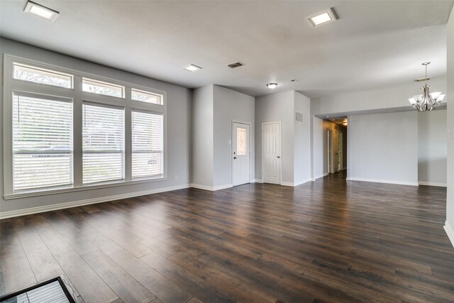 unfurnished living room featuring a chandelier, baseboards, visible vents, and dark wood finished floors