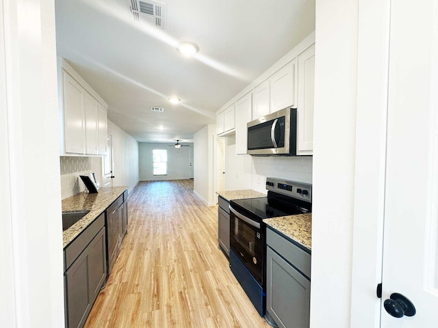 2408 Miller St, Denison, TX 75020 - kitchen with stainless steel microwave, light wood-type flooring, visible vents, decorative backsplash, and range with electric stovetop