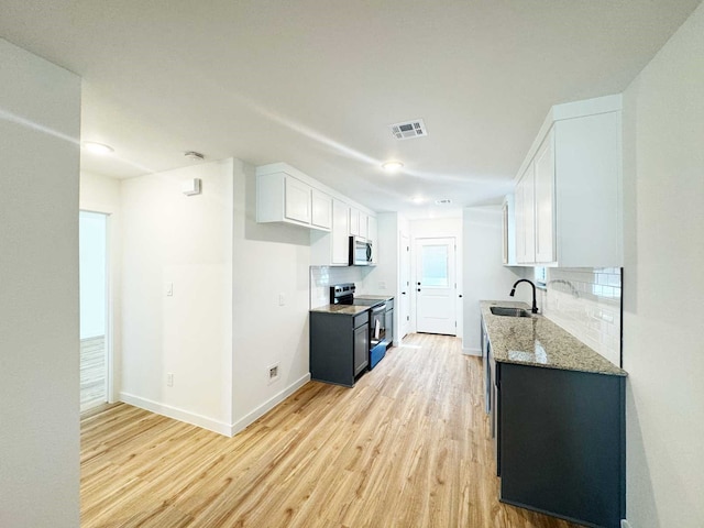 2408 Miller St, Denison, TX 75020 - kitchen with light wood finished floors, a sink, range with electric cooktop, stainless steel microwave, and light stone countertops