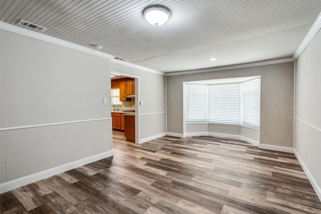 spare room featuring crown molding, dark wood-type flooring, and visible vents