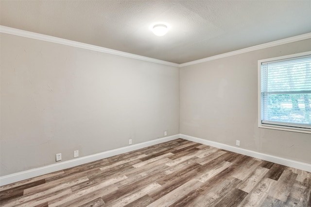 unfurnished room with baseboards, ornamental molding, wood finished floors, and a textured ceiling