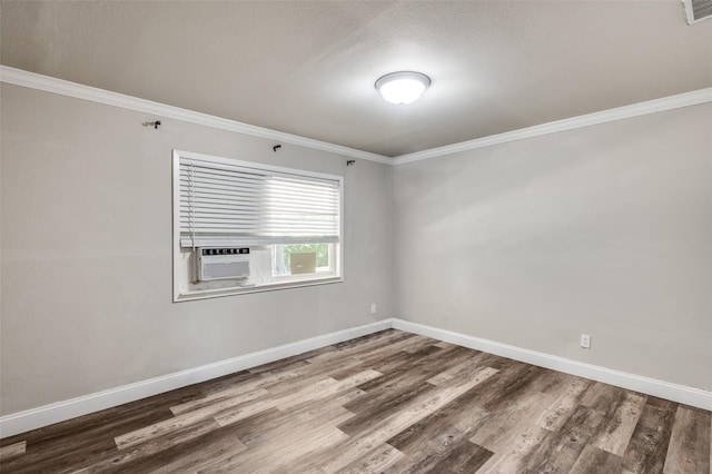 empty room featuring baseboards, wood finished floors, and crown molding