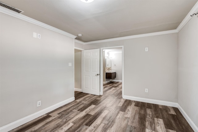 empty room with baseboards, ornamental molding, wood finished floors, and visible vents
