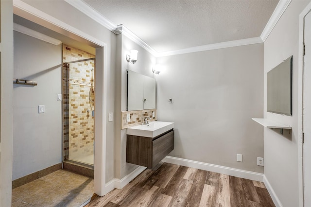 bathroom with wood finished floors, vanity, crown molding, a textured ceiling, and a stall shower