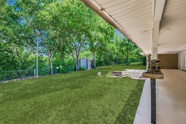 view of yard with a patio area, a shed, a fire pit, an outdoor structure, and a fenced backyard